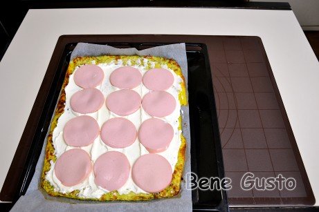 Даем остыть, а затем смазываем сливочным сыром и выкладываем колбасу. Затем скручиваем рулет.